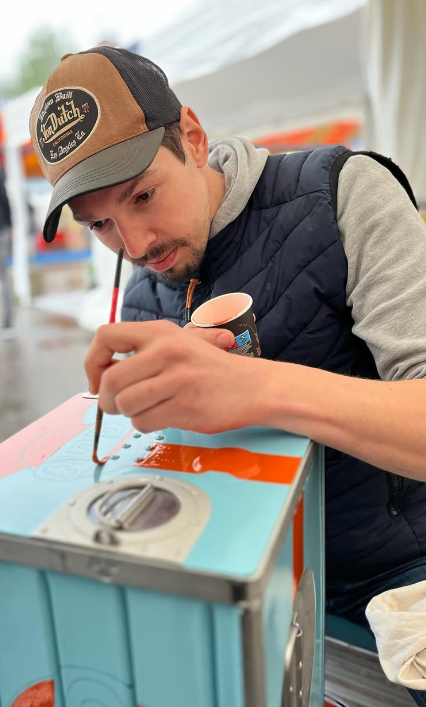 Mathieu Ollevier knowned as Vintage Addict handpainting a vintage automotive decoration with gulf colors