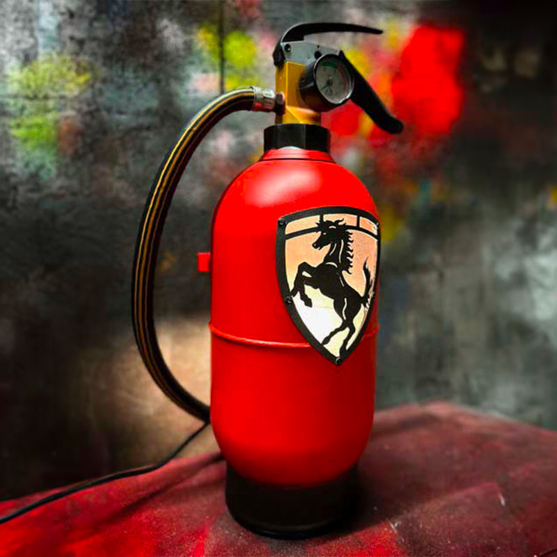 Fire extinguisher upcycled in a an automotive decoration lamp. Handpainted in red by Jean-Luc Rossier (JLR Concept) customized with the Ferrari logo. Side view with yellow light.