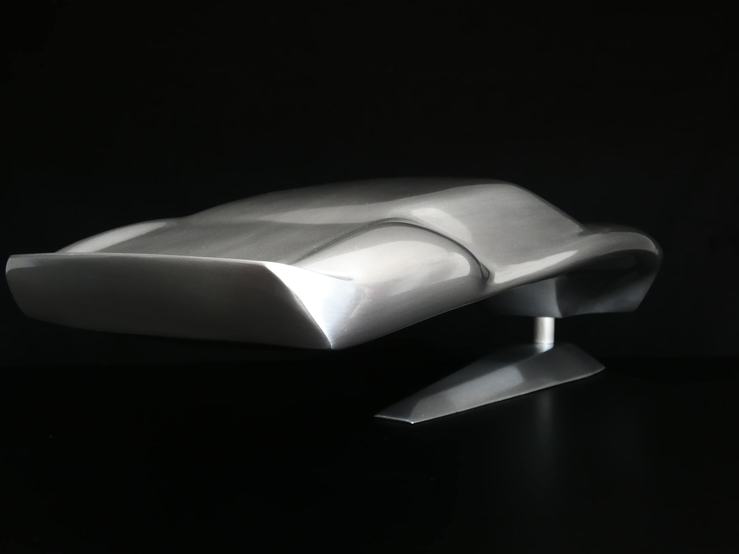 Metal sheet automotive sculpture with raw aluminium representing a Ford GT40 evocation, created by Frédéric Girard, limited edition of 8, 45x19 cm format. Tail 3/4 view showcasing the iconic curves and the meticulous attention to each sculpted detail, a collector’s piece for automotive and fine craftsmanship enthusiasts.
