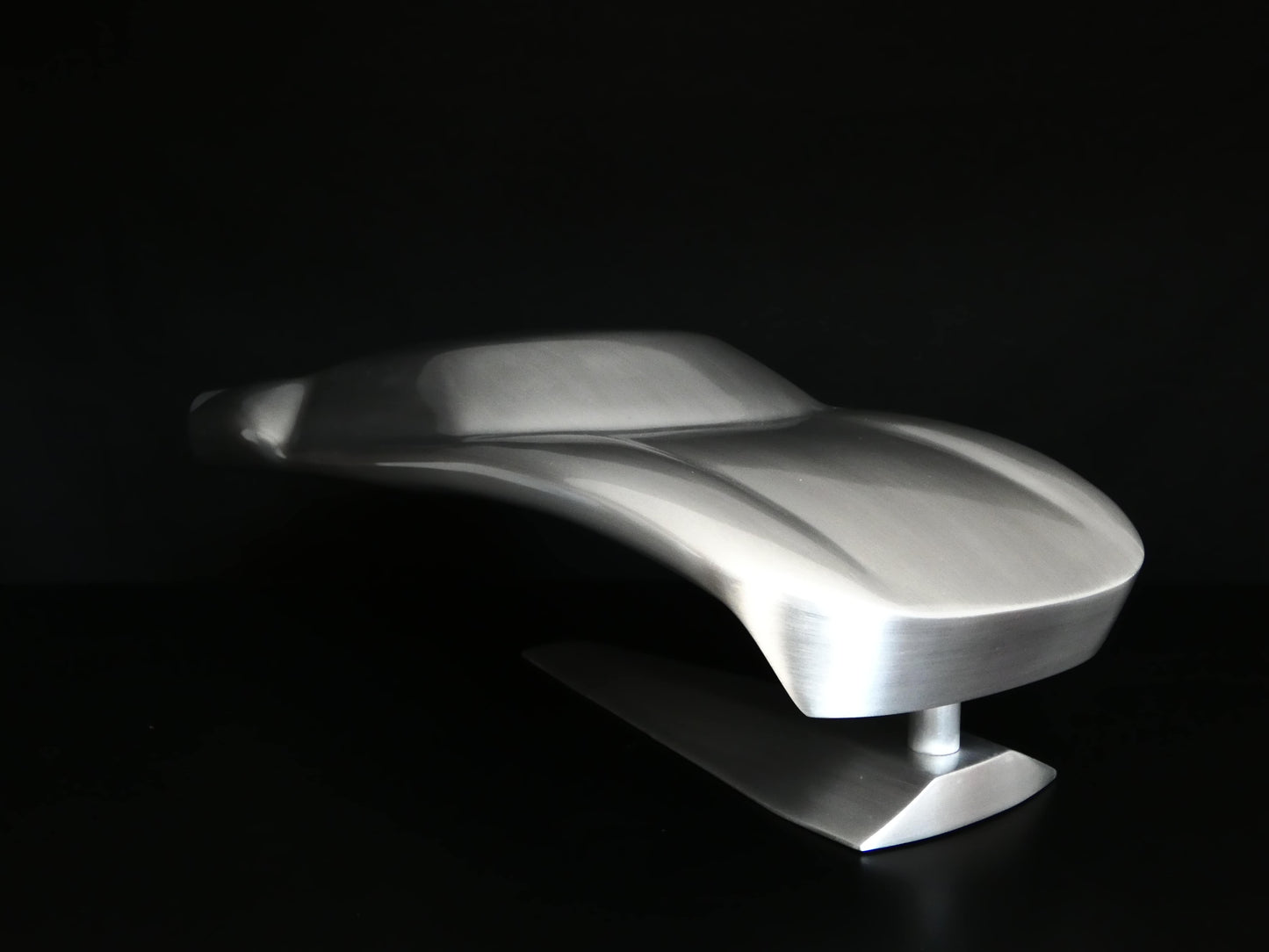 Metal sheet automotive sculpture with raw aluminium representing a Ford GT40 evocation, created by Frédéric Girard, limited edition of 8, 45x19 cm format. Nose 3/4 left view showcasing the iconic curves and the meticulous attention to each sculpted detail, a collector’s piece for automotive and fine craftsmanship enthusiasts.