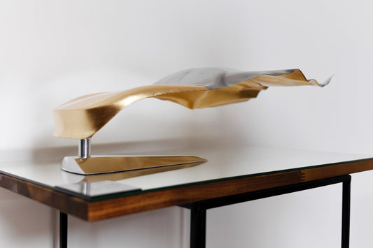 Metal sheet automotive sculpture with silver and gold finish representing GT draped, created by Frédéric Girard, limited edition of 8, 45 x 19 cm format. Side 3/4 view showcasing the iconic curves and the meticulous attention to each sculpted detail, a collector’s piece for automotive and fine craftsmanship enthusiasts.