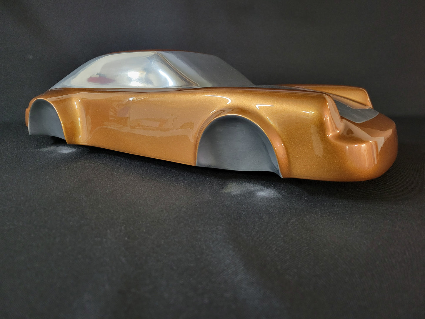 Metal sheet automotive sculpture with silver and gold finish representing a Porsche 911 Flat 6, created by Frédéric Girard, limited edition of 8, 58x25 cm format. Side view showcasing the iconic curves and the meticulous attention to each sculpted detail, a collector’s piece for automotive and fine craftsmanship enthusiasts.