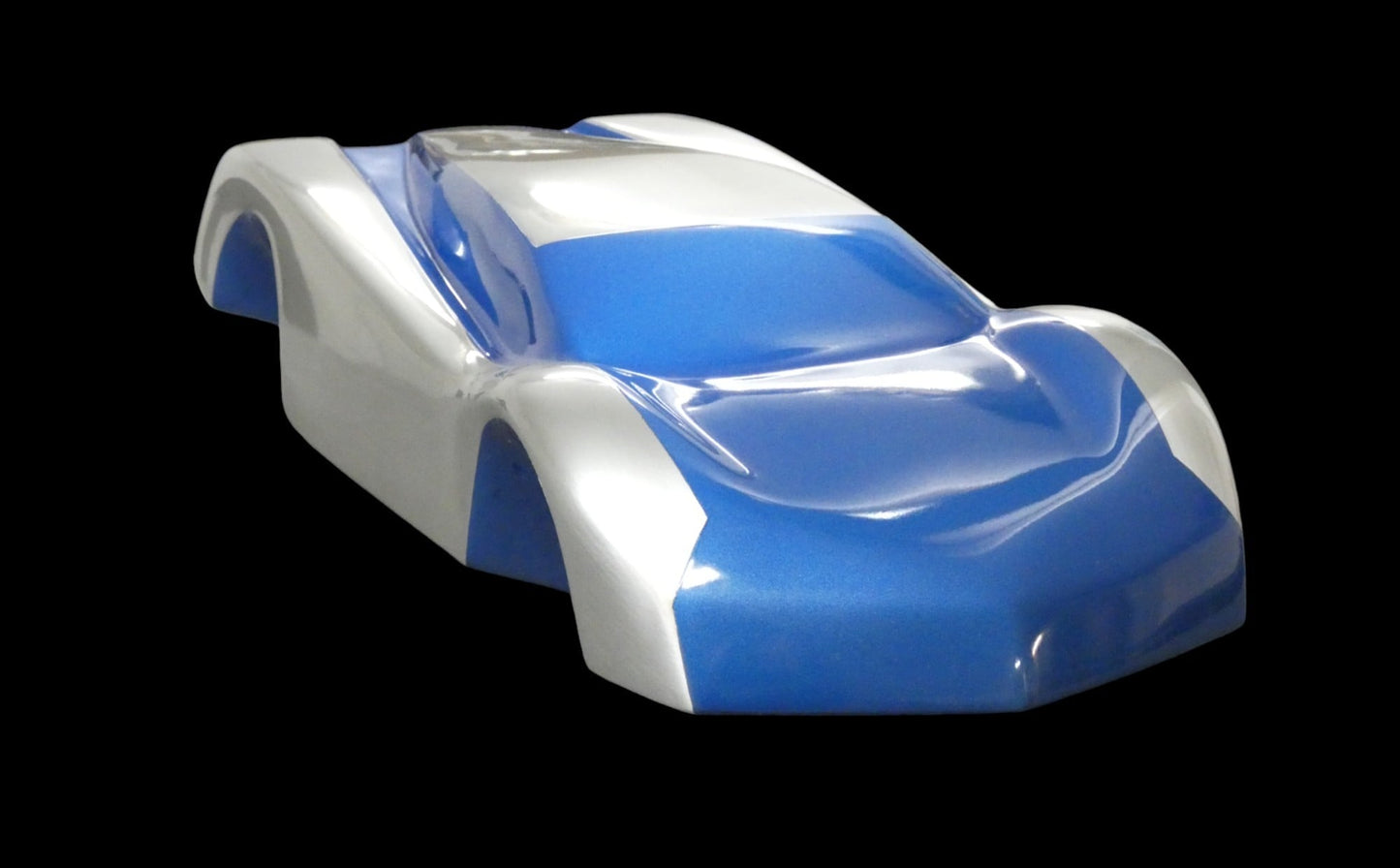 Metal sheet automotive sculpture with silver and gold finish representing V12 supercar, created by Frédéric Girard, limited edition of 8, 45 x 19 cm format. 3/4 front view showcasing the iconic curves and the meticulous attention to each sculpted detail, a collector’s piece for automotive and fine craftsmanship enthusiasts.
