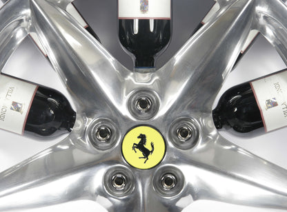 Car wheel rim bottle display stand made from a Ferrari 360 Modena wheel rim. This automotive art object measures 55x24 cm. Custom-made and handcrafted by Car2Art. Ideal for automotive art collectors. It can hold five bottles of wine or spirits. Focus on the Ferrari logo.