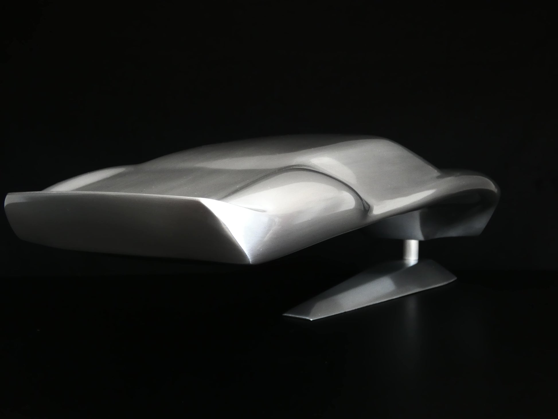 Metal sheet automotive sculpture with raw aluminium representing a Ford GT40 evocation, created by Frédéric Girard, limited edition of 8, 45x19 cm format. Tail 3/4 view showcasing the iconic curves and the meticulous attention to each sculpted detail, a collector’s piece for automotive and fine craftsmanship enthusiasts.