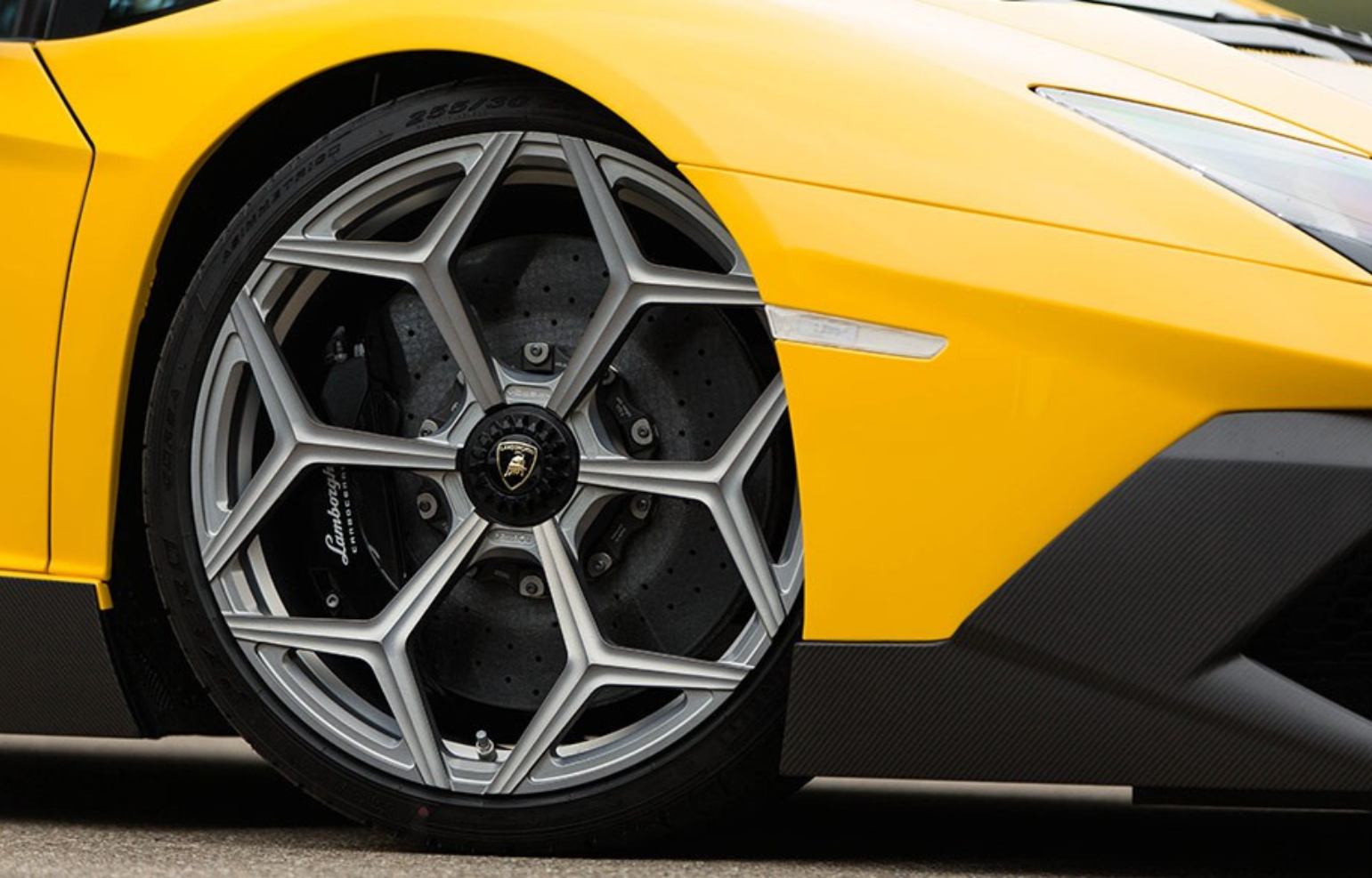Close-up of the rim and wheel on the side of a yellow Lamborghini Aventador. Highlighting the aesthetics and aggressive design of the Italian supercar